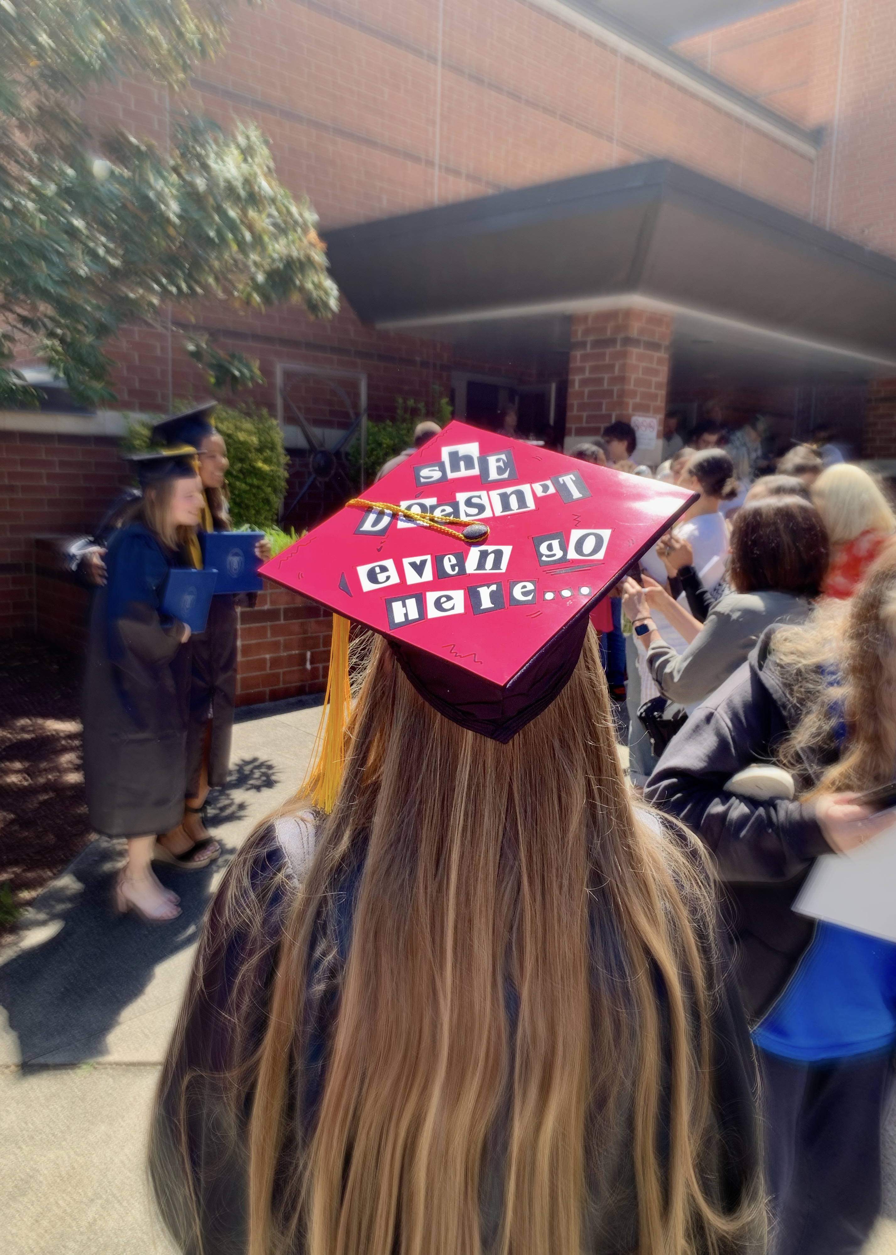 Picture of Sarah from behind, so her pink Mean Girls graduation cap is visible.